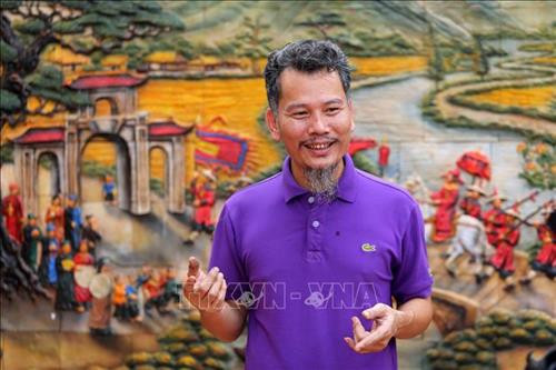 Chân dung nghệ nhân Lưu Xuân Khuyến bên bức tranh gốm văn hoá dân gian Việt Nam. Ảnh: Thành Đạt – TTXVN