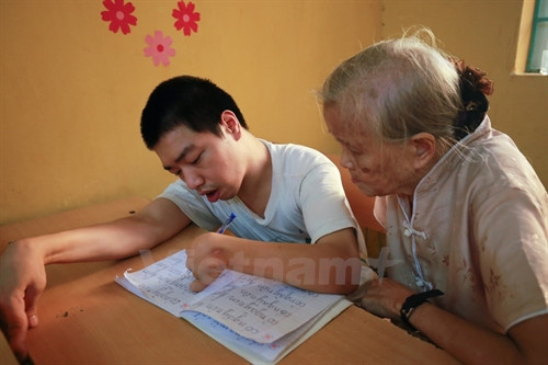 Khác với học sinh thường, những em học sinh khuyết tật được bà tận tình cầm tay, chỉ dẫn, uốn nắn từng chữ O, chữ A. (Ảnh: Minh Sơn/Vietnam+) Khác với học sinh thường, những em học sinh khuyết tật được bà tận tình cầm tay, chỉ dẫn, uốn nắn từng chữ O, chữ A. (Ảnh: Minh Sơn/Vietnam+)