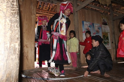 Vào cửa nhà chú rể, cô dâu bước qua tấm trải bằng lá chuối bọc than đỏ và tấm vải trắng do hai người cao tuổi giữ. Vào cửa nhà chú rể, cô dâu bước qua tấm trải bằng lá chuối bọc than đỏ và tấm vải trắng do hai người cao tuổi giữ.