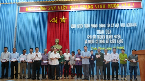 Đồng chí Nguyễn Đức Lợi trao sổ tiết kiệm cho các gia đình chính sách. Ảnh: Trần Tĩnh-TTXVN