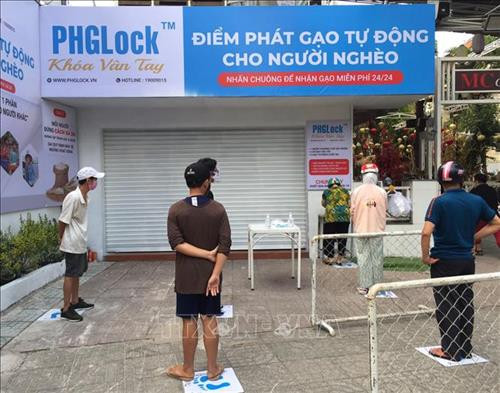 Người dân thực hiện nghiêm túc việc giãn cách 2m khi xếp hàng nhận gạo miễn phí. Ảnh: Hứa Chung - TTXVN