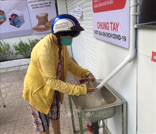 Một người phụ nữ bán vé số nhận gạo miễn phí. Ảnh: Hứa Chung -TTXVN