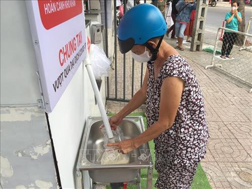 Người dân chỉ cần nhấn nút thông minh sẽ có khoảng 1,5kg gạo được chảy ra từ "ATM gạo". Ảnh: Hứa Chung - TTXVN