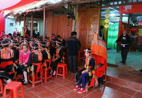 Cô dâu (trùm đầu) ngồi trước cửa nhà chú rể để thầy cúng thực hiện các nghi thức trong lễ cưới. Cô dâu (trùm đầu) ngồi trước cửa nhà chú rể để thầy cúng thực hiện các nghi thức trong lễ cưới.