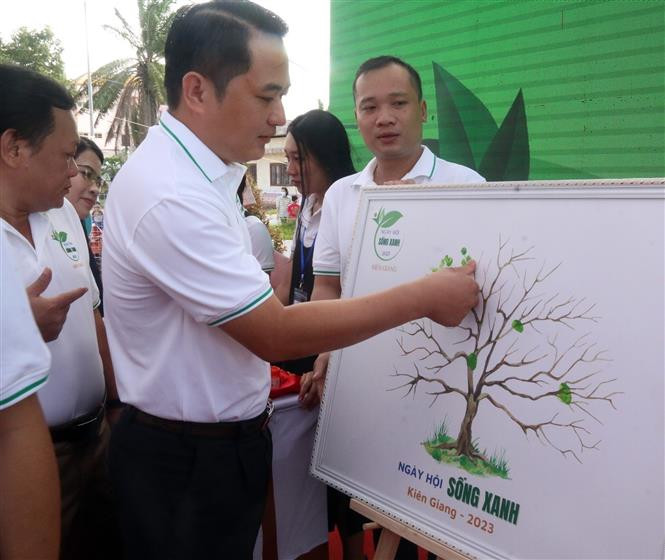 Các đại biểu thực hiện nghi thức “phủ xanh” tán cây tại Ngày hội. Ảnh: Lê Sen - TTXVN Kiên Giang: Đổi rác lấy quà trong "Ngày hội sống xanh" ảnh 3
