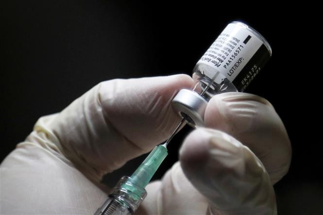 Nhân viên y tế chuẩn bị mũi tiêm vaccine ngừa COVID-19 của Pfizer tại một điểm tiêm chủng ở Toronto, Canada ngày 14/12/2020. Ảnh: AFP/TTXVN Canada cho phép tiêm liều tăng cường vaccine ngừa COVID-19 cho trẻ 5-11 tuổi ảnh 1
