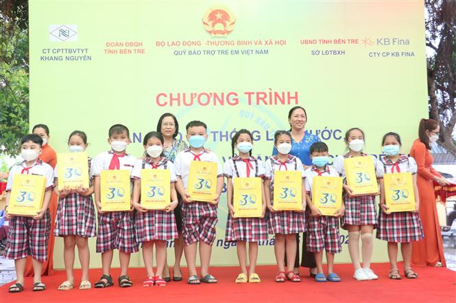Các đơn vị trao quà cho các em học sinh có hoàn cảnh khó khăn trên địa bàn huyện Thạnh Phú, Bến Tre. Ảnh: Công Trí - TTXVN Mang nước sạch đến học đường vùng biển mặn ảnh 2