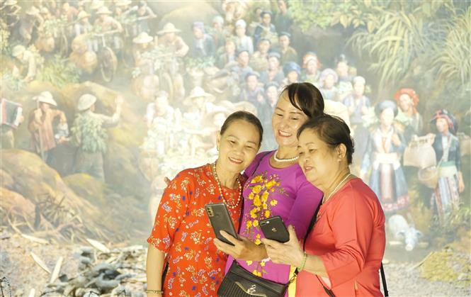 Du khách chụp ảnh lưu niệm với bức tranh Panorama Chiến dịch Điện Biên Phủ. Ảnh: Xuân Tư - TTXVN Sức hút từ Bức tranh Panorama Chiến dịch Điện Biên Phủ ảnh 2