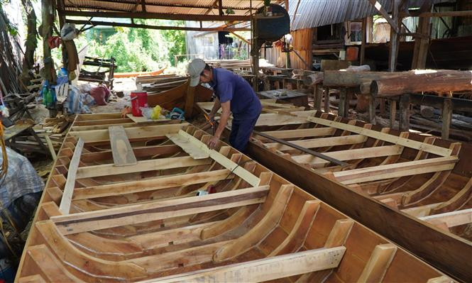 Nhiều cơ sở đóng xuồng, ghe ở rạch Bà Đài chỉ còn hoạt động cầm chừng. Ảnh: Nhựt An - TTXVN Đìu hiu làng nghề đóng xuồng, ghe trăm tuổi ảnh 1