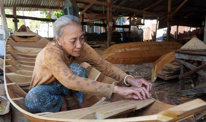 Bà Trần Kim Bé tại xã Long Hậu (Lai Vung, Đồng Tháp) trét dầu chai - một trong những công đoạn để hoàn thành chiếc xuồng. Ảnh: Nhựt An - TTXVN Đìu hiu làng nghề đóng xuồng, ghe trăm tuổi ảnh 2