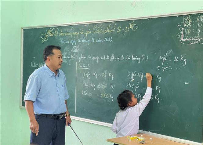 Thầy Nguyễn Thanh Tuấn chỉ dạy cho học sinh. Ảnh: Đinh Hương - TTXVN Ngày Nhà giáo Việt Nam 20/11: Cha và con thầy giáo cùng hành trình "gieo chữ" nơi vùng cao Trà Bồng ảnh 2
