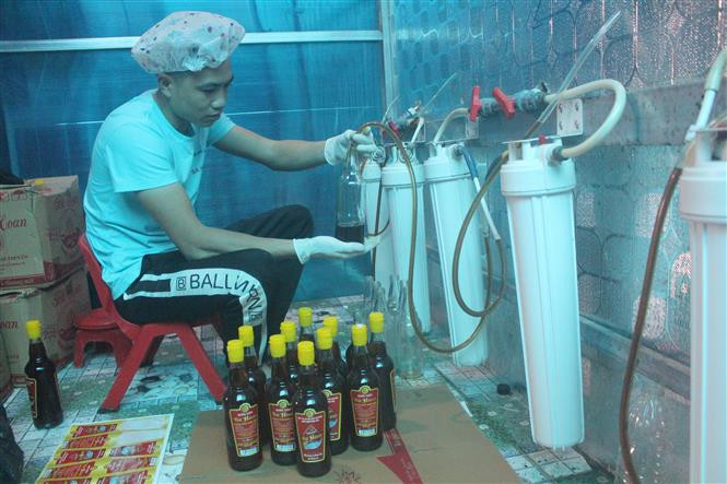 Công đoạn đóng nước mắm vào chai. Ảnh: Khiếu Tư -TTXVN Làng nghề nước mắm truyền thống Khúc Phụ tất bật vào vụ Tết ảnh 2