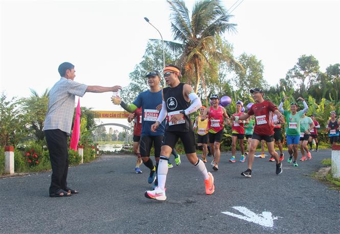 Người dân tặng đặc sản cho các vận động viên trên đường chạy 42 km giải Marathon quốc tế Vietcombank Mekong Delta - Hậu Giang 2022. Ảnh: Hồng Thái - TTXVN Sức bật Hậu Giang ảnh 4