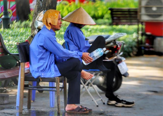Cái khăn mặt ướt cùng chai nước là vật không thể thiếu của những nhân viên trông xe vỉa hè ở Hà Nội. Ảnh: Tuấn Đức - TTXVN Chuyên gia hướng dẫn bảo vệ sức khỏe trong những ngày nắng nóng ảnh 2