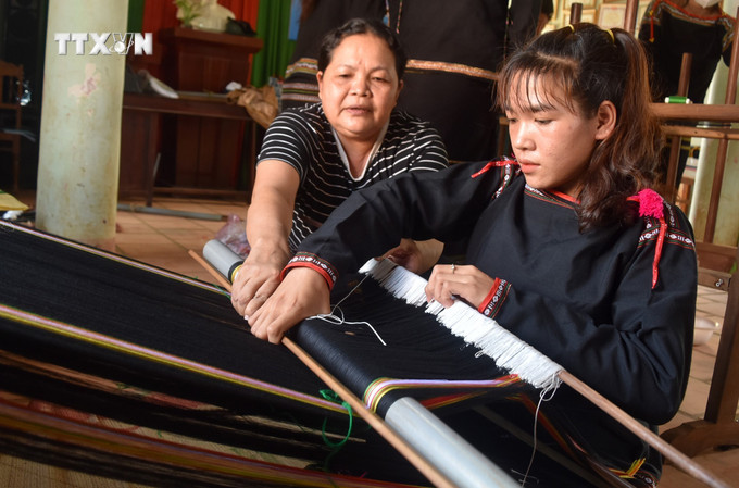 Hướng dẫn học viên bước cơ bản của nghề dệt thổ cẩm. Ảnh: Nguyên Dung - TTXVN vna_potal_dak_lak_dao_tao_nghe_trao_sinh_ke_giup_nguoi_dan_giam_ngheo_7374869.jpg