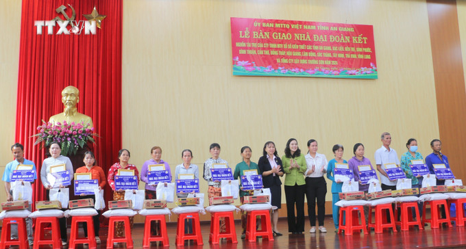 Bà Đặng Thị Hoa Rây, Chủ tịch Ủy ban Mặt trận Tổ quốc Việt Nam tỉnh An Giang (thứ 10 trái qua) cùng đại diện nhà tài trợ và chính quyền địa phương trao Quyết định tặng nhà "Đại đoàn kết" và quà cho các hộ dân. Ảnh: Công Mạo-TTXVN vna_potal_an_giang_ban_giao_145_can_nha_dai_doan_ket_cho_ho_ngheo_kho_khan_ve_nha_o_7725970.jpg
