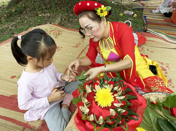 Hướng dẫn thiếu nhi trải nghiệm têm trầu cánh phượng tại Phiên chợ. Ảnh: Trần Lê Lâm – TTXVN DN4.jpg