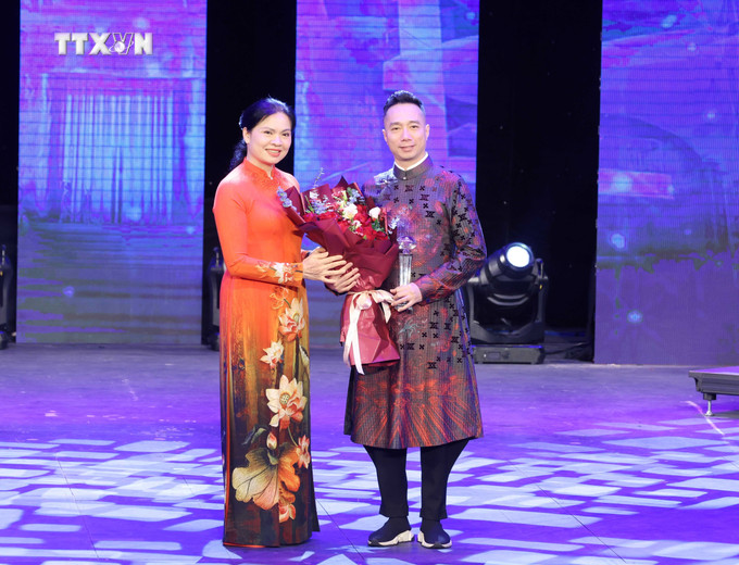 Đồng chí Hà Thị Nga, Uỷ viên Trung ương Đảng, Chủ tịch Hội Liên hiệp Phụ nữ Việt Nam tặng Kỷ niệm chương cho nhà thiết kế Đỗ Trịnh Hoài Nam. Ảnh: Phương Hoa - TTXVN vna_potal_le_phat_dong_“tuan_le_ao_dai”_va_chuong_trinh_nghe_thuat_“huong_sac_ao_dai_viet”_7248950.jpg