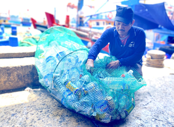 Ngư dân thu gom, vận chuyển rác thải nhựa từ tàu cá vào bờ. Ảnh: TTXVN phát binhdinh1.jpg