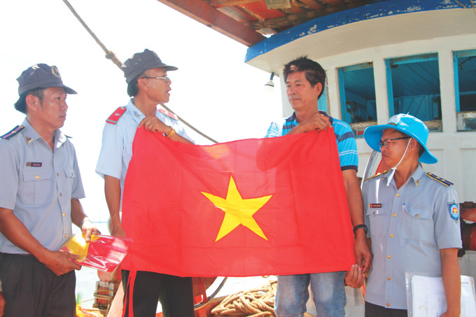 Lực lượng kiểm ngư tỉnh Bạc Liêu trao tặng cờ Tổ quốc đến các chủ tàu và thuyền trưởng, qua đó động viên, khuyến khích ngư dân tiếp tục vươn khơi bám biển. Ảnh: Danh Chanh Đa 4-tau ca Bac Lieu-danh chanh da.JPG