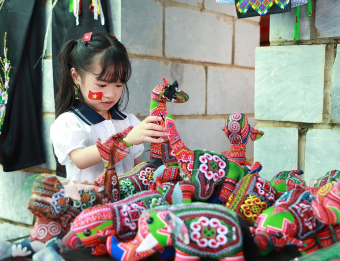 Em nhỏ thích thú với đồ chơi thủ công của đồng bào Mông. rucro-sacmau2.jpg