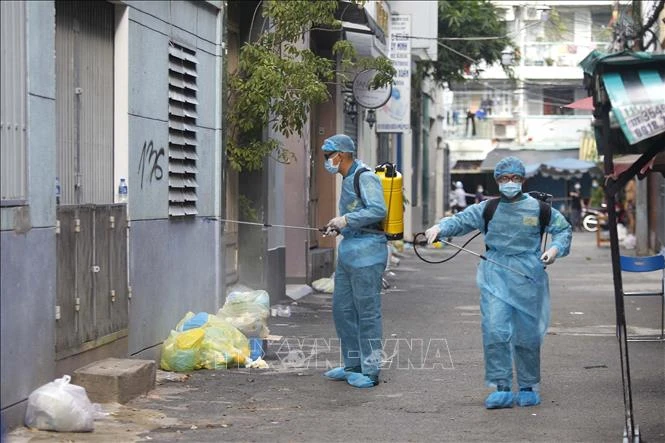Các lực lượng chức năng phun xịt, khử khuẩn toàn bộ khu vực phong tỏa cách ly tại hẻm 611 đường Điện Biên Phủ, phường 1, Quận 3. Ảnh: Thanh Vũ – TTXVN