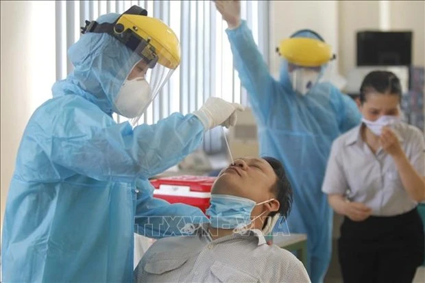Các y bác sỹ Trung tâm y tế Quận 7 thực hiện xét nghiệm sàng lọc COVID-19 ngẫu nhiên cho công nhân tại Công ty TNHH Kim may Organ Việt Nam. Ảnh: Thanh Vũ - TTXVN