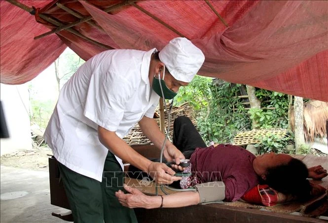Cán bộ quân y Đồn biên phòng Phúc Sơn (huyện Anh Sơn) đến thăm khám tận nhà cho những người già neo đơn, người khuyết tật không thế đến trạm xá khám. Ảnh: Văn Tý-TTXVN