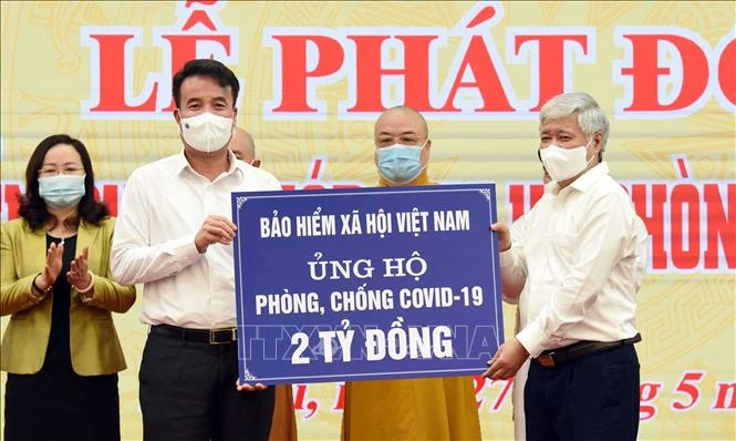 Chủ tịch Ủy ban Trung ương Mặt trận tổ quốc Việt Nam Đỗ Văn Chiến (bên phải) tiếp nhận 2 tỷ đồng của BHXH Việt Nam ủng hộ. Ảnh: TTXVN