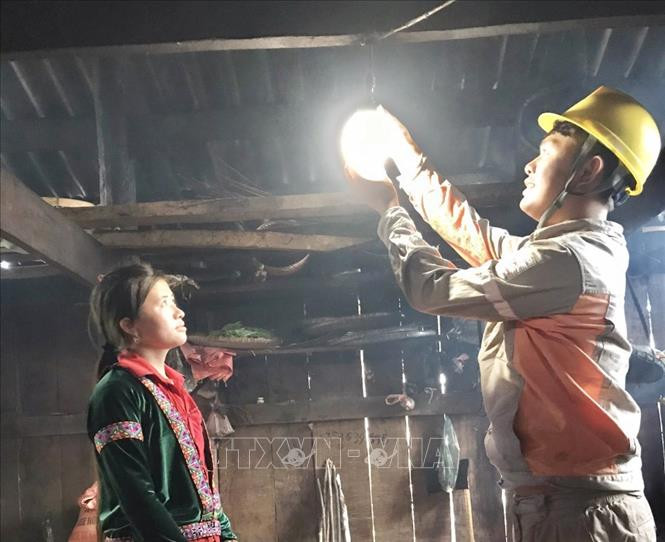 Công nhân Công ty Điện lực Lai Châu thay bóng đèn miễn phí cho người dân. Ảnh: Nguyễn Oanh - TTXVN
