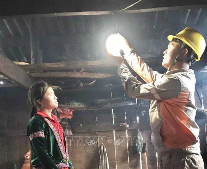 Công nhân Công ty Điện lực Lai Châu thay bóng đèn miễn phí cho người dân. Ảnh: Nguyễn Oanh - TTXVN