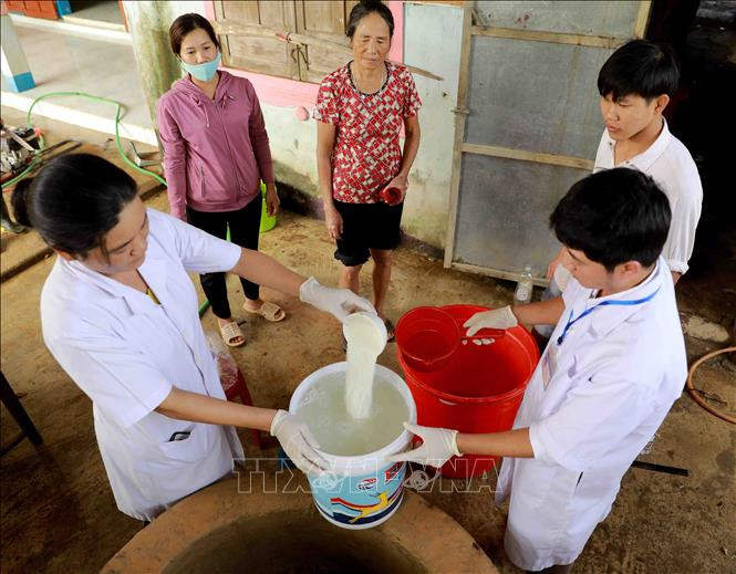 Nhân viên Trung tâm Y tế dự phòng huyện Lệ Thủy tiến hành khử khuẩn nước sinh hoạt bằng dung dịch Cloramin B cho hộ Lê Thị Đào ở thôn Mai Thúy, xã Mai Thủy. Ảnh: Vũ Sinh - TTXVN