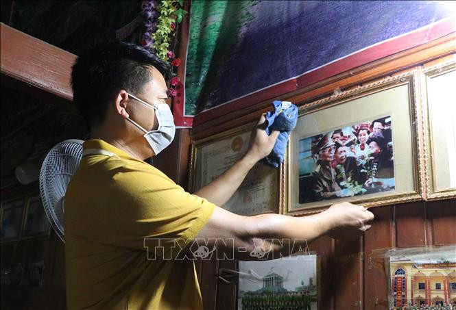 Anh Lò Văn Ánh (bản Phăng 2, xã Mường Phăng, thành phố Điện Biên Phủ, tỉnh Điện Biên) lau lại bức ảnh bà nội là cụ Lò Thị Đôi được chụp chung với Đại tướng trong lần Đại tướng lên thăm lại Điện Biên lần cuối vào năm 2004. Ảnh: Xuân Tiến – TTXVN 