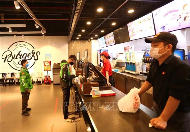 Các cửa hàng ăn, uống trong TTTM BigC Thăng Long yêu cầu khách hàng đứng giãn cách và chỉ bán hàng mang về. Ảnh: Hoàng Hiếu – TTXVN