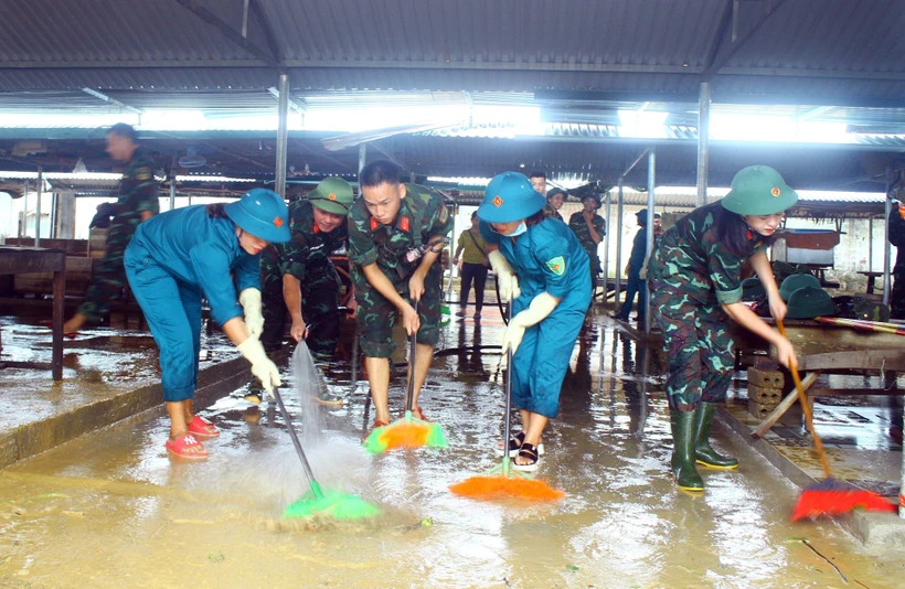Lực lượng quân đội, dân quân tự vệ đẩy bùn đất, tổng dọn vệ sinh tại chợ xã Thanh Mỹ, huyện Thanh Chương (Nghệ An). Ảnh: Tá Chuyên - TTXVN