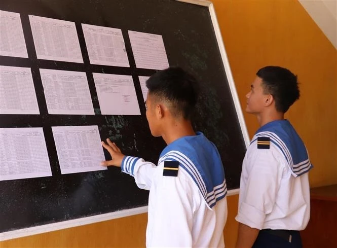 Hai chiến sỹ trẻ lần đầu tiên được đi bầu, theo dõi danh sách cử tri được niêm yết tại UBND xã Song Tử Tây, huyện Trường Sa (Khánh Hòa). Ảnh: TTXVN