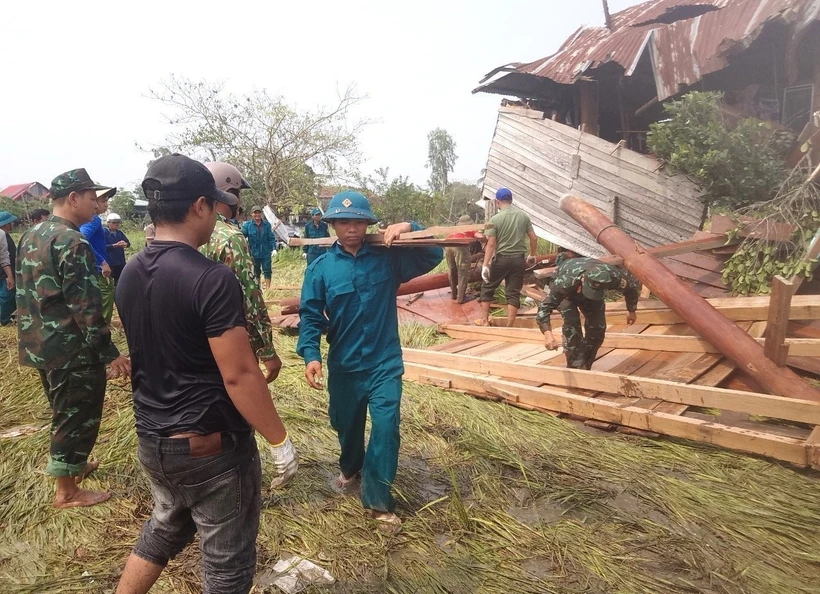 Các lực lượng chức năng hỗ trợ người dân khắc phục thiệt hại do mưa dông, lốc. Ảnh: TTXVN phát