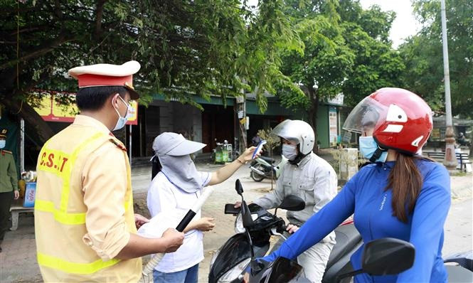 Kiểm tra thân nhiệt chủ phương tiện tại chốt kiểm soát dịch bệnh COVID-19 ở địa điểm cổng chào thành phố Vĩnh Yên giáp với huyện Vĩnh Tường (Vĩnh Phúc). Ảnh: Hoàng Hùng - TTXVN