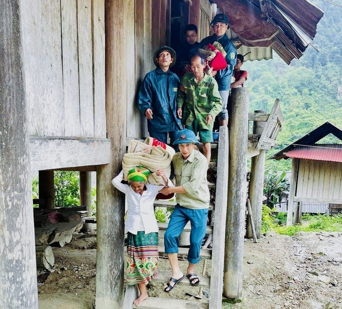 Lực lượng chức năng hỗ trợ người dân di chuyển đồ đạc, vật dụng di dời đến Nhà văn hóa cộng đồng của bản tạm trú để tránh nguy cơ sạt lở núi, lũ quét. Ảnh: TTXVN phát xoi-voi-210725-1.jpg