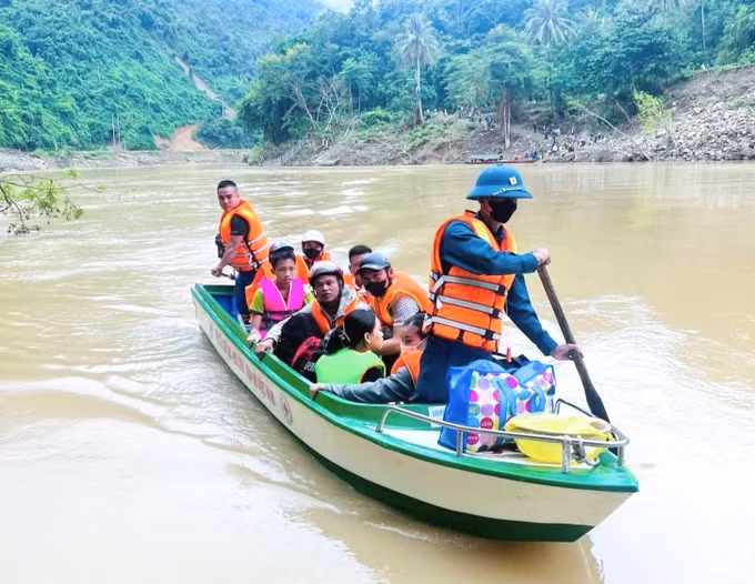 Lực lượng công an, dân quân và các ban, ngành đoàn thể xã Lượng Minh (tỉnh Nghệ An) hỗ trợ đưa học sinh, giáo viên qua sông Nậm Nơn bằng thuyền cứu trợ của Hội Chữ thập đỏ Việt Nam. Ảnh: TTXVN phát