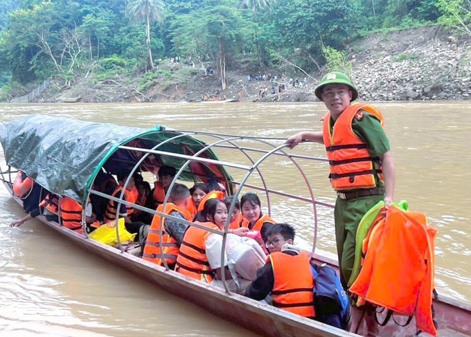 Lực lượng công an đưa, đón học sinh, giáo viên qua sông Nậm Nơn bằng thuyền khi cầu treo bản Xốp Mạt (xã Lượng Minh) bị lũ cuốn trôi trong đợt mưa bão cuối tháng 7 vừa qua. Ảnh: TTXVN phát nghe-an-030925-3.jpg