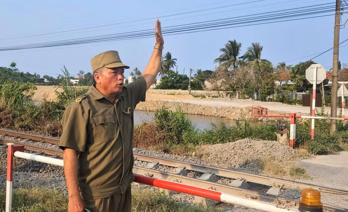 Ông Nguyễn Văn Sang, thành viên tổ “gác chắn tự quản” ra hiệu an toàn cho tàu đi qua.