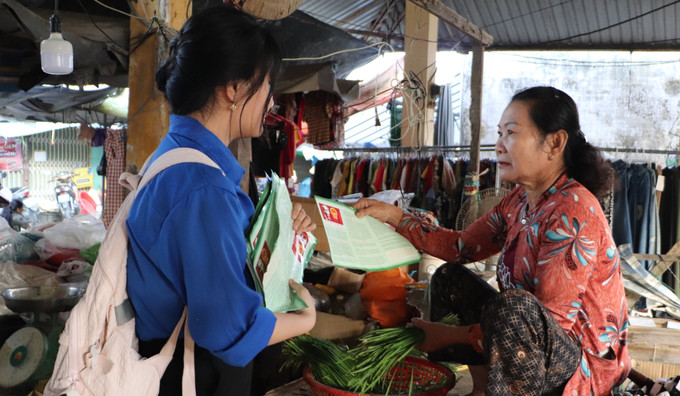 Đoàn viên, thanh niên xã Vĩnh Thuận Đông phát tờ rơi tuyên truyền về bầu cử tại chợ trung tâm xã. Ảnh: Hồng Thái/TTXVN