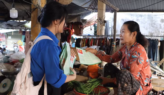 Đoàn viên, thanh niên xã Vĩnh Thuận Đông phát tờ rơi tuyên truyền về bầu cử tại chợ trung tâm xã. Ảnh: Hồng Thái/TTXVN