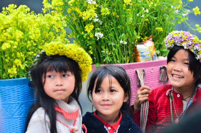 Những em bé với chiếc gùi đầy hoa cải vàng trên lưng chơi ở dốc Thẩm Mã. Ảnh: Nam Thái - TTXVN Mùa hoa cải vàng rực cao nguyên đá Hà Giang ảnh 8