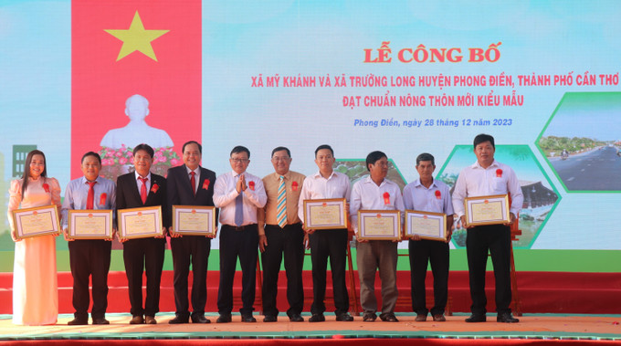 Lãnh đạo thành phố Cần Thơ tặng Bằng khen cho các tập thể, cá nhân có nhiều đóng góp trong xây dựng nông thôn mới ở Mỹ Khánh và Trường Long. Ảnh: Thu Hiền - TTXVN Cần Thơ có thêm 2 xã nông thôn mới kiểu mẫu ảnh 2