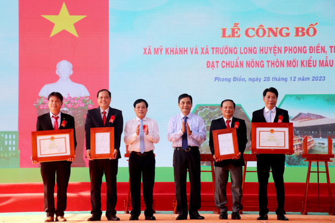 Lãnh đạo thành phố Cần Thơ trao Quyết định công nhận xã nông thôn mới kiểu mẫu cho đại diện lãnh đạo xã Mỹ Khánh và Trường Long. Ảnh: Thu Hiền - TTXVN Cần Thơ có thêm 2 xã nông thôn mới kiểu mẫu ảnh 1