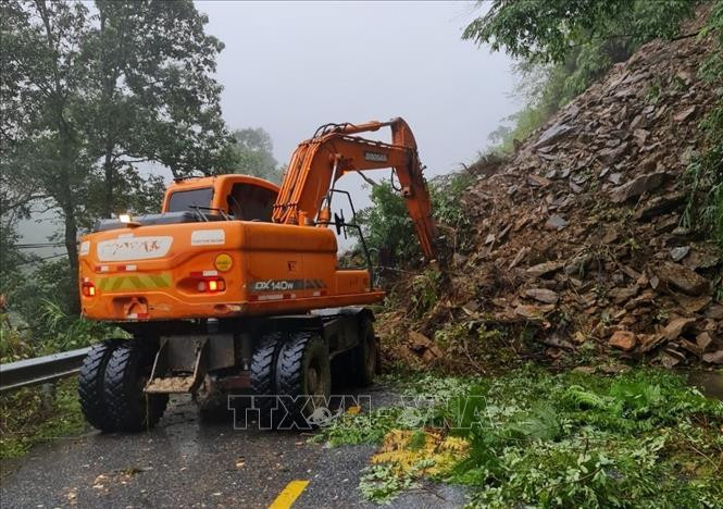 Lực lượng chức năng triển khai phương tiện máy móc tiến hành khắc phục sạt lở trên Đèo Khau Phạ thuộc địa phận xã Cao Phạ, huyện Mù Cang Chải. Ảnh: TTXVN phát Sạt lở đất đá gây ách tắc trên đèo Khau Phạ ảnh 2