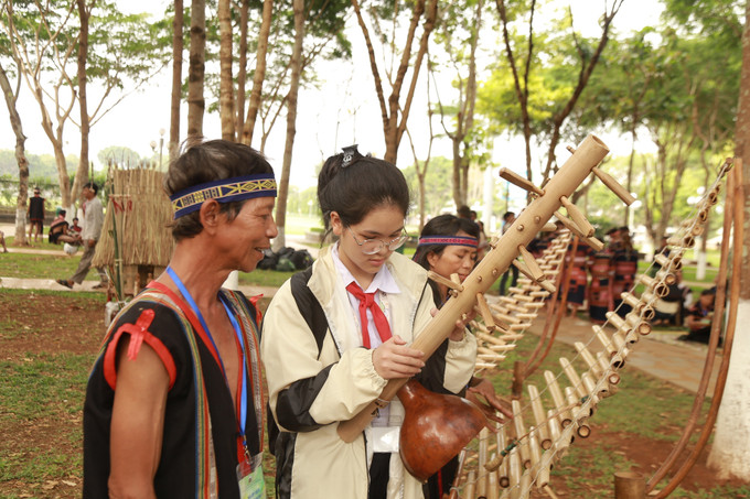 Em Đặng Thị Minh Châu (lớp 7- Trường THCS Nguyễn Huệ, thành phố Pleiku, tỉnh Gia Lai) tìm hiểu thanh âm của cây đàn Goong. Ảnh: Quang Thái- TTXVN Gia Lai bảo tồn và quảng bá văn hóa truyền thống của đồng bào dân tộc thiểu số ảnh 7