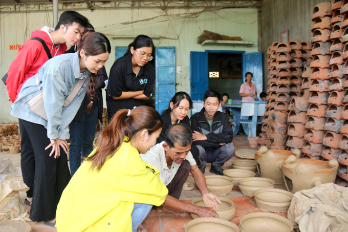 Các bạn trẻ tìm hiểu nghệ thuật làm gốm chăm tại nhà Nghệ nhân Lâm Hùng Sổi, làng gốm Bình Đức. Ảnh: Nguyễn Thanh - TTXVN Chung tay gìn giữ, bảo tồn và phát huy di sản Nghệ thuật làm gốm Chăm ảnh 5